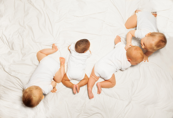 view from top of four babies backs crawling in row